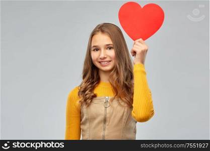 valentine&rsquo;s day, love and people concept - smiling young teenage girl with red heart over grey background. smiling teenage girl with red heart