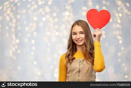 valentine&rsquo;s day, love and people concept - smiling young teenage girl with red heart over festive lights background. smiling teenage girl with red heart