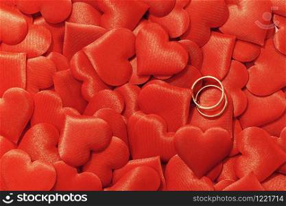 Valentine&rsquo;s day many red silk hearts background with two gold rings, love concept