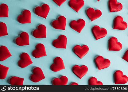 Valentine&rsquo;s day many red silk hearts on blue paper background, love concept. Valentines day hearts on blue