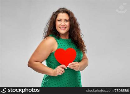 valentine&rsquo;s day, people and love concept - happy woman in green dress holding red heart over grey background. happy woman in green dress holding red heart