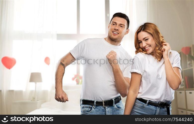 valentine&rsquo;s day, relationships and people concept - happy couple in white t-shirts dancing over bedroom decorated with heart shaped balloons background. happy couple dancing on valentines day in bedroom