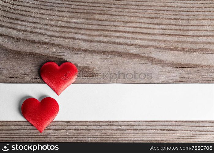 Valentine&rsquo;s day two red silk hearts and white paper on wooden background, love concept. Valentines day hearts on wood