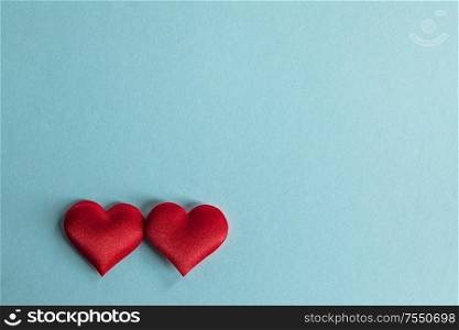Valentine&rsquo;s day two red silk hearts on blue paper background, love concept. Valentines day hearts on blue