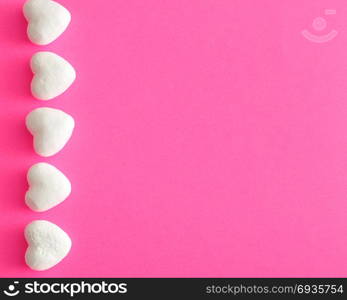 Valentine&rsquo;s Day. White polystyrene hearts on a pink background