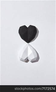 Valentine&rsquo;s holiday card with two plaster hearts white and black on a light gray background with hard shadows, copy space. Top view. Valentine&rsquo;s day greeting card.. Two gypsum hearts black and white with shadows.