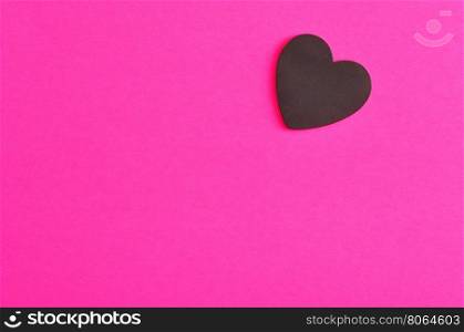 Valentine's Day. A black heart isolated on a pink background