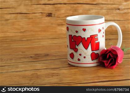 Valentine's Day. A white mug with the word love on it with an artificial rose