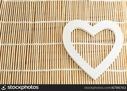 Valentine's Day. A white wooden heart isolated against a bamboo background