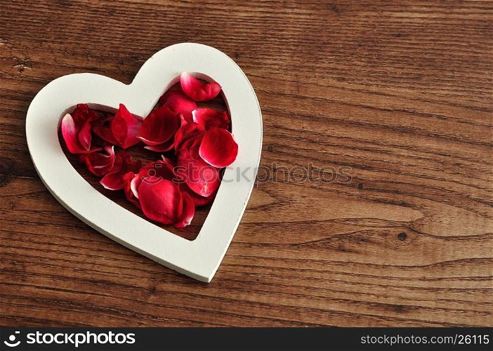 Valentine's Day. A white wooden hearts filled with red rose petals