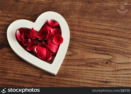 Valentine's Day. A white wooden hearts filled with red rose petals