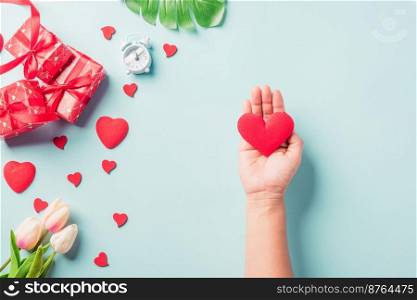 Valentine’s day and birthday. Woman hands holding red heart and have gift or present box decorated surprise on blue background, Female’s hand hold heart have gift box package in craft paper