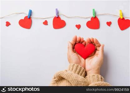 Valentine’s day and birthday. Woman hands holding red heart present decorated surprise on white background, Female’s hand hold gift heart on hands, Top view flat lay composition