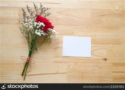 Valentine’s day concept, Red roses flower bouquet and blank white note paper on wood background with copy space , Banner for mock up, template, top view, flate lay
