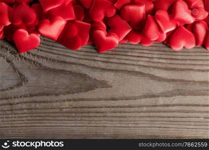 Valentine’s day many red silk hearts on wooden background, love concept. Valentines day hearts background
