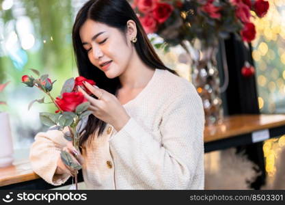 valentine’s day,Portrait Happy Smiling beautiful Asian young woman wearing warm clothes holding bouquet of red roses with rose vase of in the living room inside or cafe