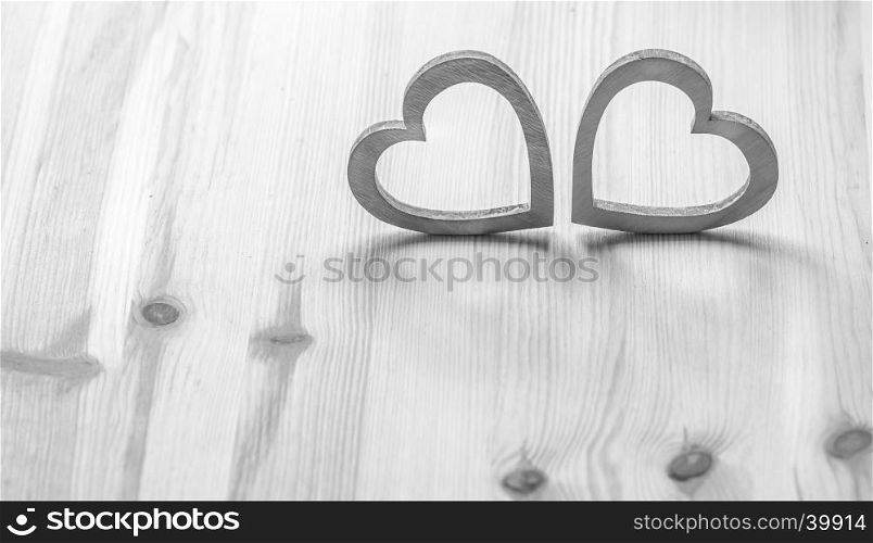 Valentine's holiday settings with two gray wooden hearts on wooden surface.