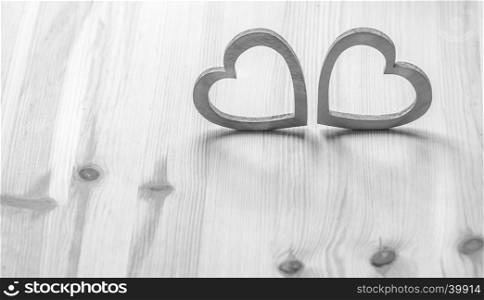 Valentine's holiday settings with two gray wooden hearts on wooden surface.
