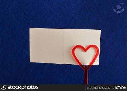 Valentines day. A note holder with a red heart with a note isolated against a blue background