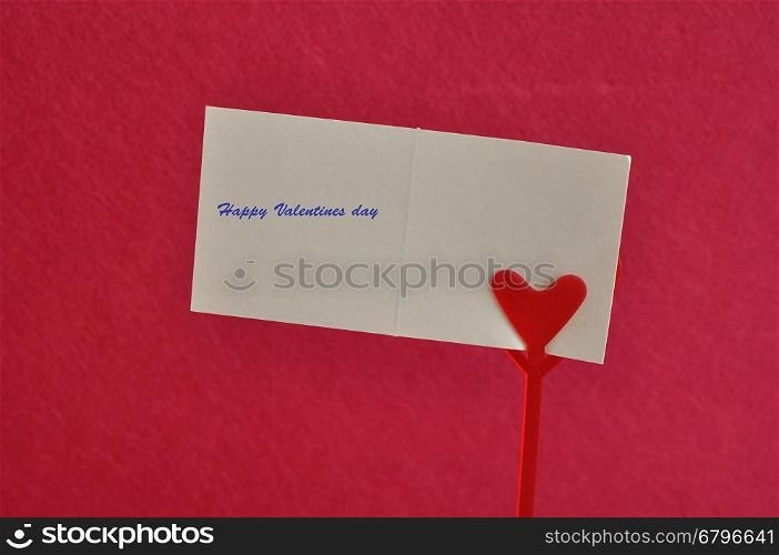 Valentines day. A note holder with a red heart with a note reading hugs and kisses isolated against a pink background
