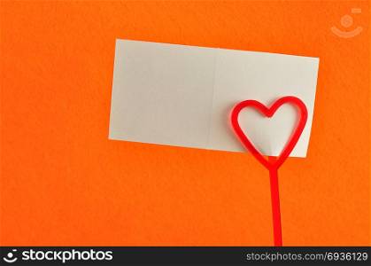 Valentines day. A note holder with a red heart with a note isolated against an orange background