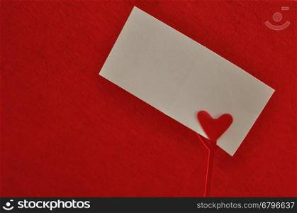 Valentines day. A note holder with a red heart with an empty card isolated against a red background