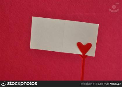 Valentines day. A note holder with a red heart with an empty card isolated against a pink background