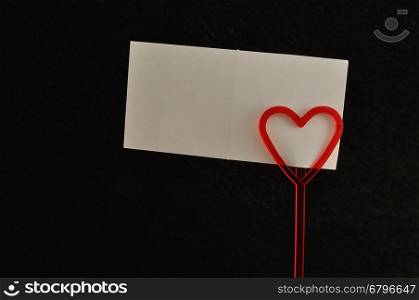 Valentines day. A note holder with a red heart with an empty card isolated against a black background