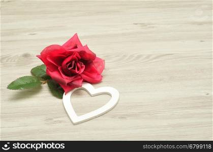 Valentines day. A white heart with an artificial red rose isolated against a wooden background