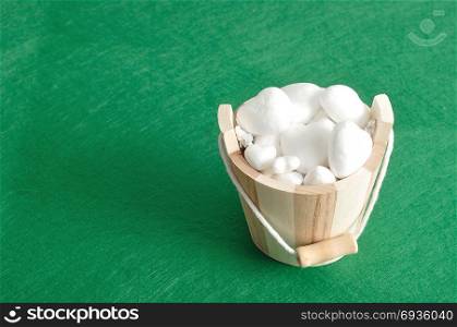 Valentines day. A wooden bucket filled with polystyrene hearts isolated against a green background