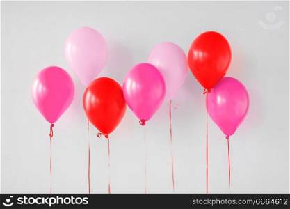valentines day and birthday party decoration concept - pink and red air balloons over white wall. pink and red air balloons for birthday party