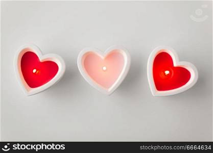 valentines day and decoration concept - heart shaped candles burning. heart shaped candles burning on valentines day