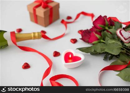 valentines day and holidays concept - close up of ch&agne, gift, red heart shaped chocolate candies, candle and red roses. close up of ch&agne, gift, candies and red roses