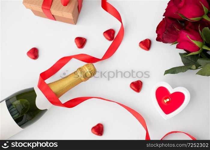 valentines day and holidays concept - close up of ch&agne, gift, red heart shaped chocolate candies, candle and red roses. close up of ch&agne, gift, candies and red roses