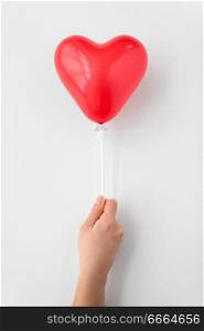 valentines day and romantic concept - close up of hand holding red heart shaped balloon on stick holder over white background. close up of hand holding red heart shaped balloon