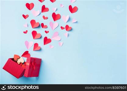 Valentines’ day background. Red gift box postcard and paper flying elements hearts cut greeting gift card isolated on blue background, Symbol of love. Top View Happy Mother’s, Valentine’s Day concept