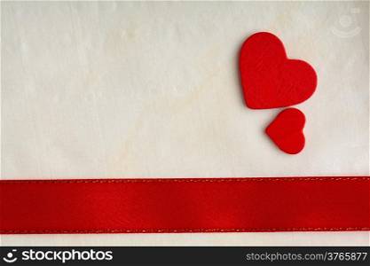 Valentines day background. Red satin ribbon with two wooden hearts on cloth. Copy space for text