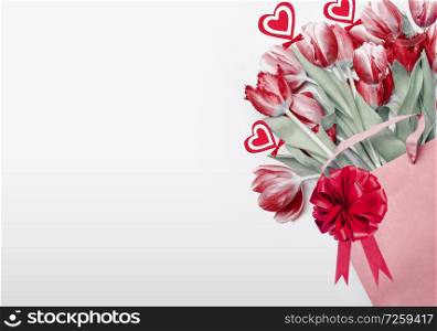 Valentines day background. Red tulips in shopping bag decorated with bow, ribbon and hearts. Holiday shopping concept. Romance floral composing. Flowers bunch. Greeting card or sale coupon.