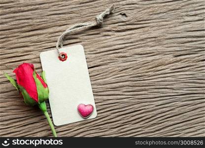 Valentines day background with heart, rose and tag on wood background.