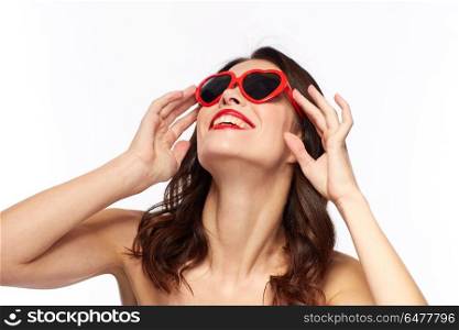valentines day, beauty and people concept - happy smiling young woman with red lipstick and heart shaped sunglasses over white background. woman with red lipstick and heart shaped shades. woman with red lipstick and heart shaped shades