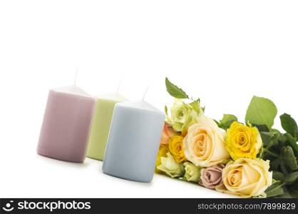 Valentines Day card background. Valentines Day card background with three candles in pastel colors alongside a bouquet of fragrant fresh yellow and green roses symbolic of love over white with copyspace for your greeting