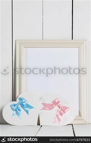 Valentines Day cards. Valentines Day heart shaped paper cards with satin ribbon bows and empty picture frame on white wooden background