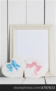Valentines Day cards. Valentines Day heart shaped paper cards with satin ribbon bows and empty picture frame on white wooden background