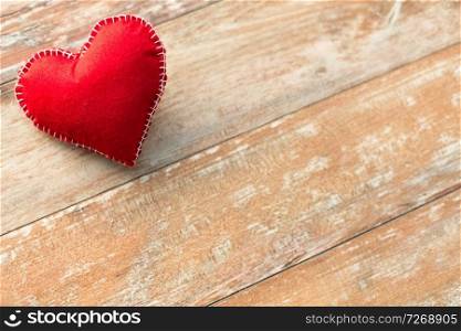 valentines day, christmas and crafting concept - heart shaped decoration stitched from red textile on wooden background. red heart shaped decoration on wooden background