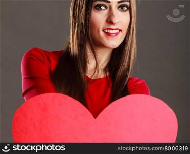 Valentines day concept. Brunette long hair young woman in red dress holding big heart love symbol dark gray background