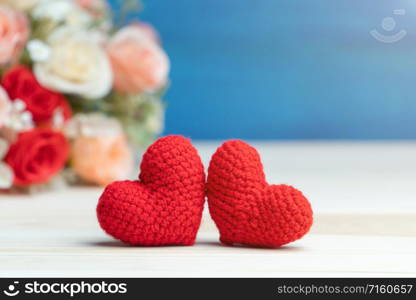Valentines day concept. hand make two yarn red heart in front of rose flower bouquet on wooden table and blue background
