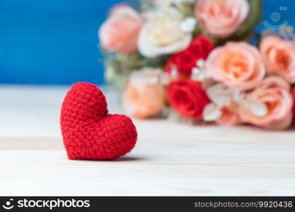 Valentines day concept. hand make yarn red heart in front of rose flower bouquet on wooden table and blue background