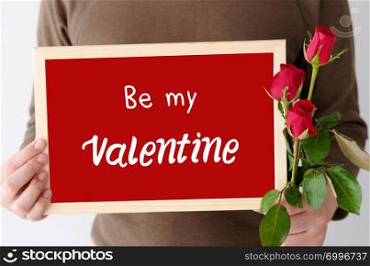 Valentines? day concept, Man hand holding red roses and Be my valentine word on wooden frame standing over white background