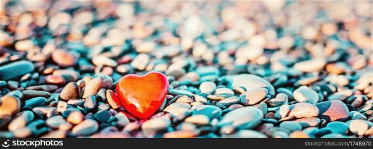 Valentines Day concept. Romantic love symbol of red heart on the pebble beach with copy space. Template for Inspirational compositions and"e postcards.