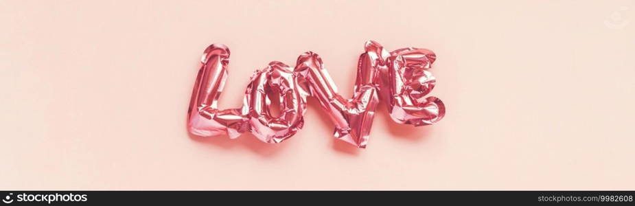 Valentines Day creative concept. Inflatable pink glossy foil balloon shaped word Love on pink background. Top view flat lay with copy space. Holiday, celebration, wedding bachelorette party decoration